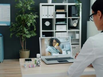 Doctor consulting patient via-video call on laptop