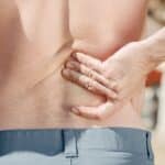 Man holding his lower back in pain, possibly indicating discomfort or injury