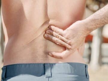 Man holding his lower back in pain, possibly indicating discomfort or injury