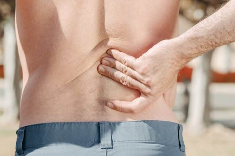 Man holding his lower back in pain, possibly indicating discomfort or injury